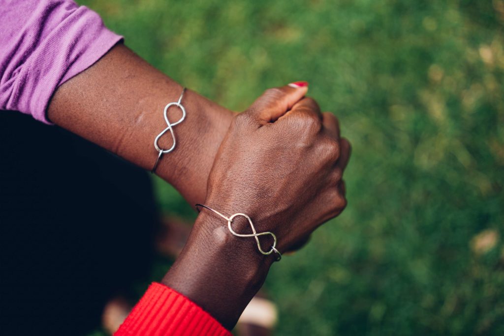 two women hold hands wearing infinity bracelet